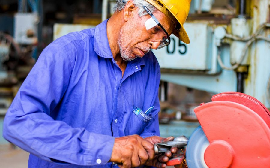 Worker grinding metal on an industrial machine